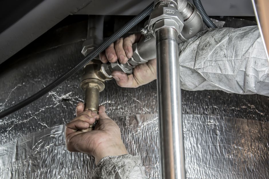 Professional plumber installing pipe fittings